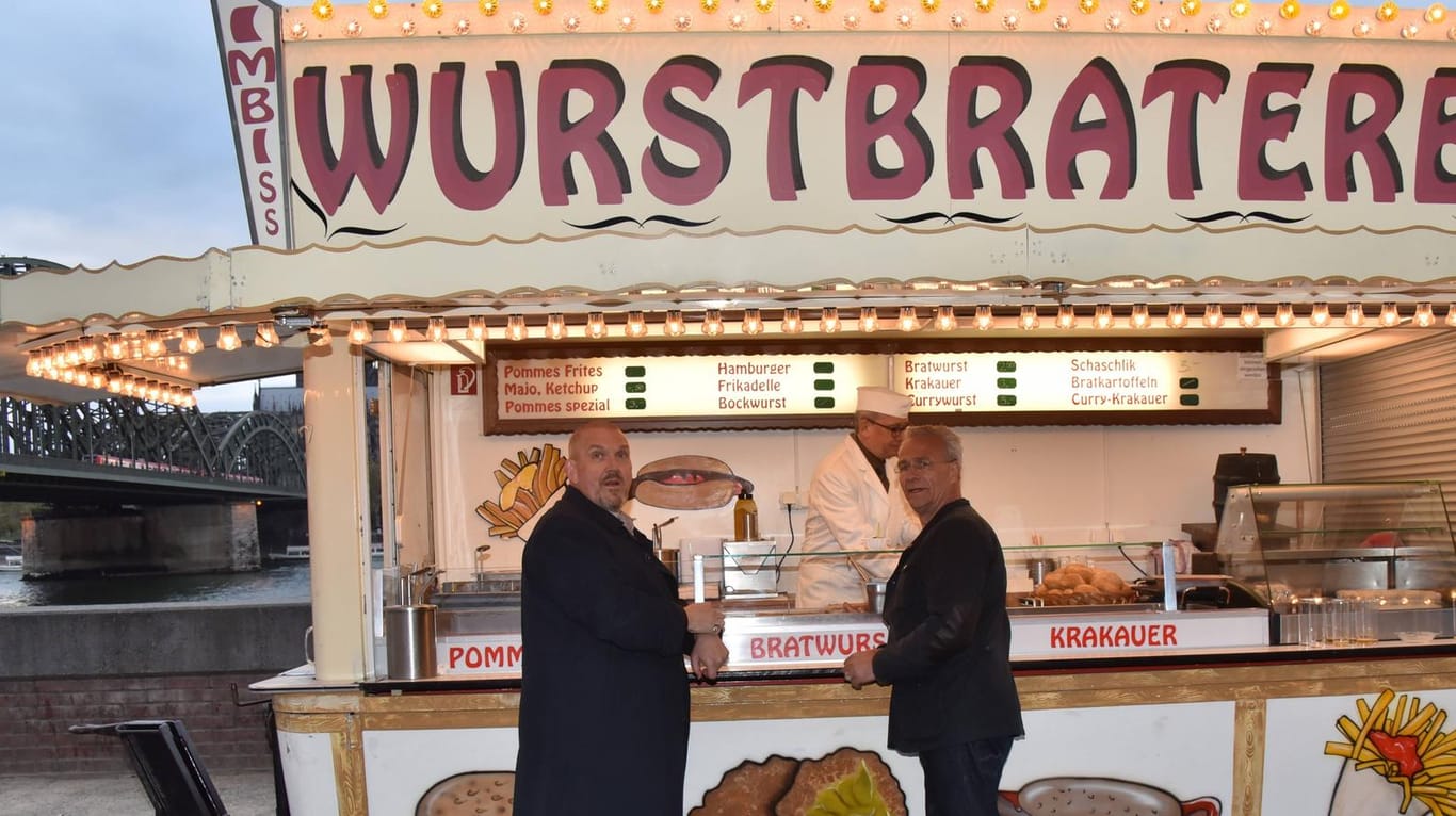 Schauspieler Dietmar Bär (links) und Klaus J. Behrendt (rechts) an einer Imbissbude: Die Wurstbraterei kommt ins Museum.