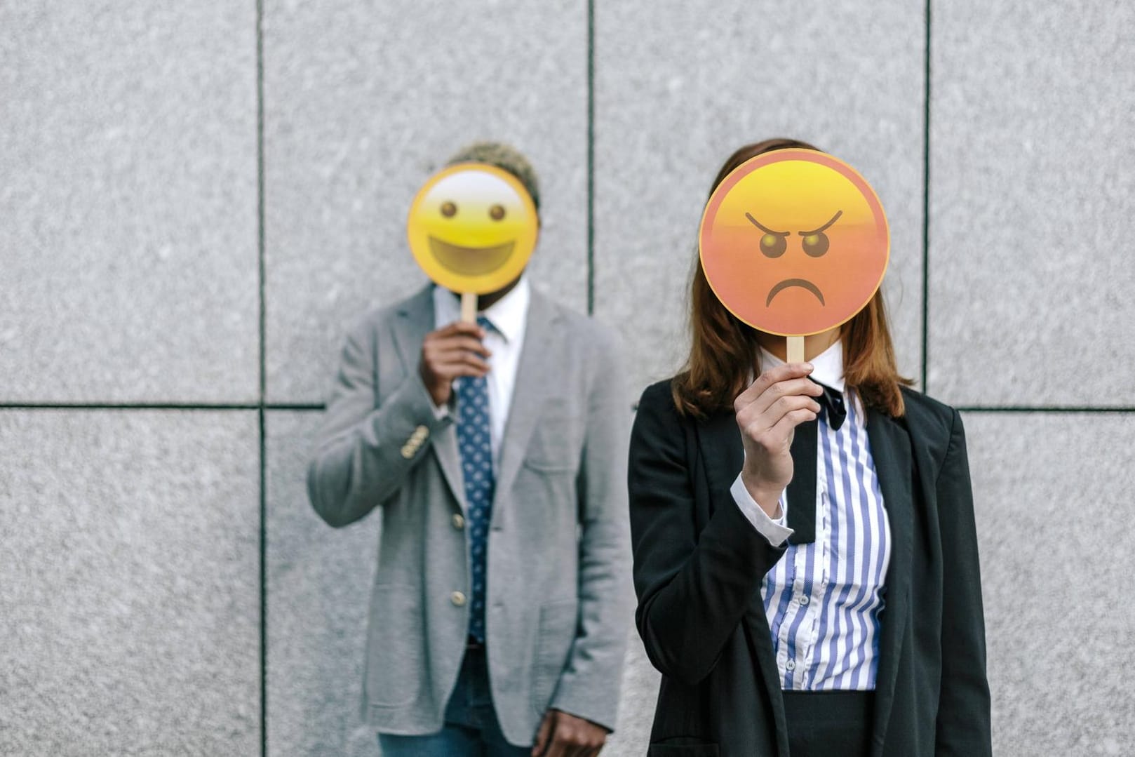 Ein Mann und eine Frau halten ein Emoji vors Gesicht: Eine exklusive Umfrage von t-online.de zeigt, wie die Deutschen zu Emojis stehen.