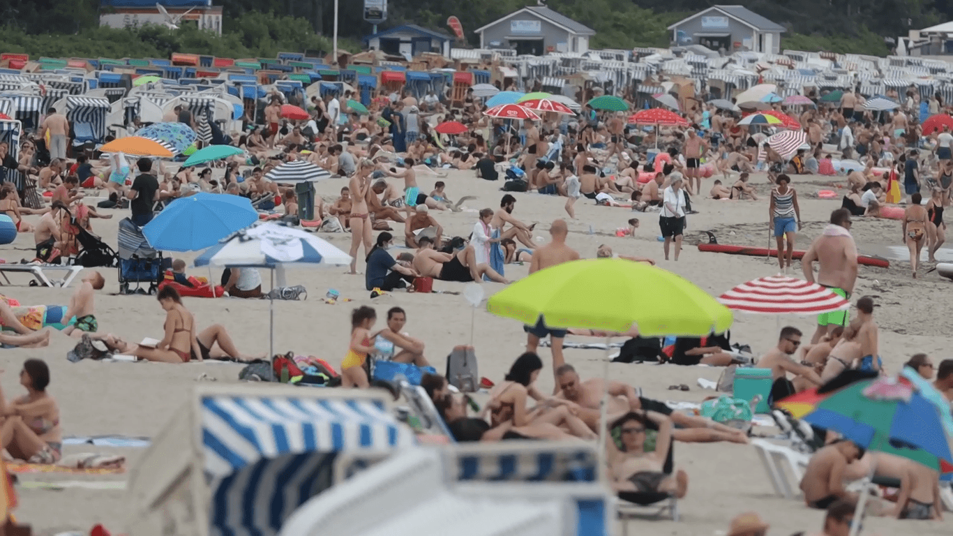 Viele Menschen liegen am Strand mit Sonnenschirmen und Strandkörben: Die Küstenregionen in Deutschland sind gut besucht.