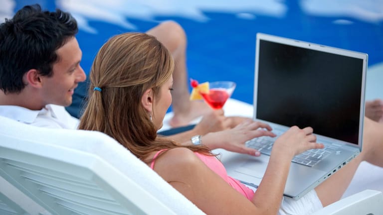 Frau mit Laptop am Pool: Bei der Nutzung des Hotel-WLANs sollte man einige Regeln beachten