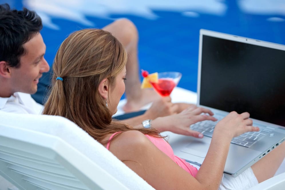 Frau mit Laptop am Pool: Bei der Nutzung des Hotel-WLANs sollte man einige Regeln beachten