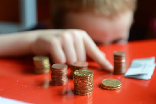 Ein Junge sortiert Kleingeld (Symbolbild): Viele Familien sind finanziell benachteiligt.