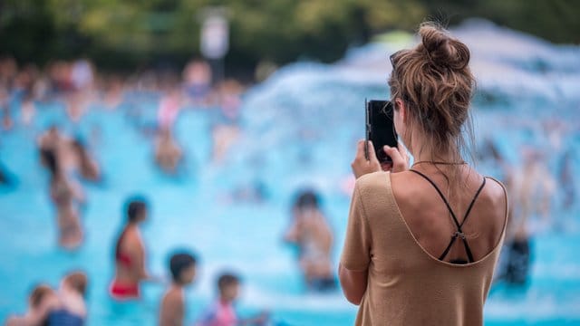 Eine junge Frau fotografiert mit ihrem Handy im Prinzenbad.