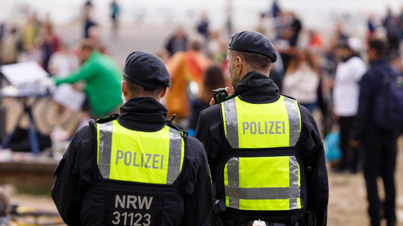 Polizisten stehen vor einer Menschenmenge (Symbolbild): In Köln will die Polizei mehr Präsenz an Party-Hotspots zeigen.