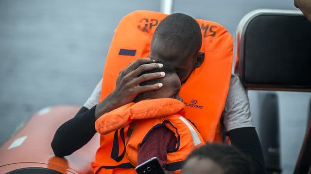 Ein Mann hält seinen Sohn im Arm, nachdem er gemeinsam mit anderen Flüchtlingen gerettet wurde. Ein Mann hält seinen Sohn im Arm, nachdem er gemeinsam mit anderen Flüchtlingen gerettet wurde.