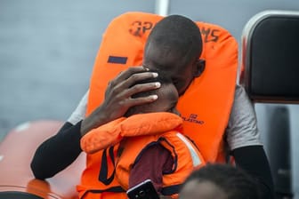 Ein Mann hält seinen Sohn im Arm, nachdem er gemeinsam mit anderen Flüchtlingen gerettet wurde.