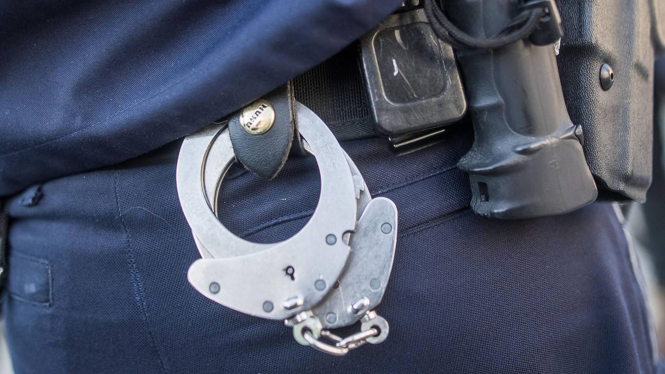 Handschellen hängen am Gürtel eines Polizisten (Symbolbild): Ein Wolfsburger wurde wegen der Verbreitung von kinderpornografischem Material festgenommen.