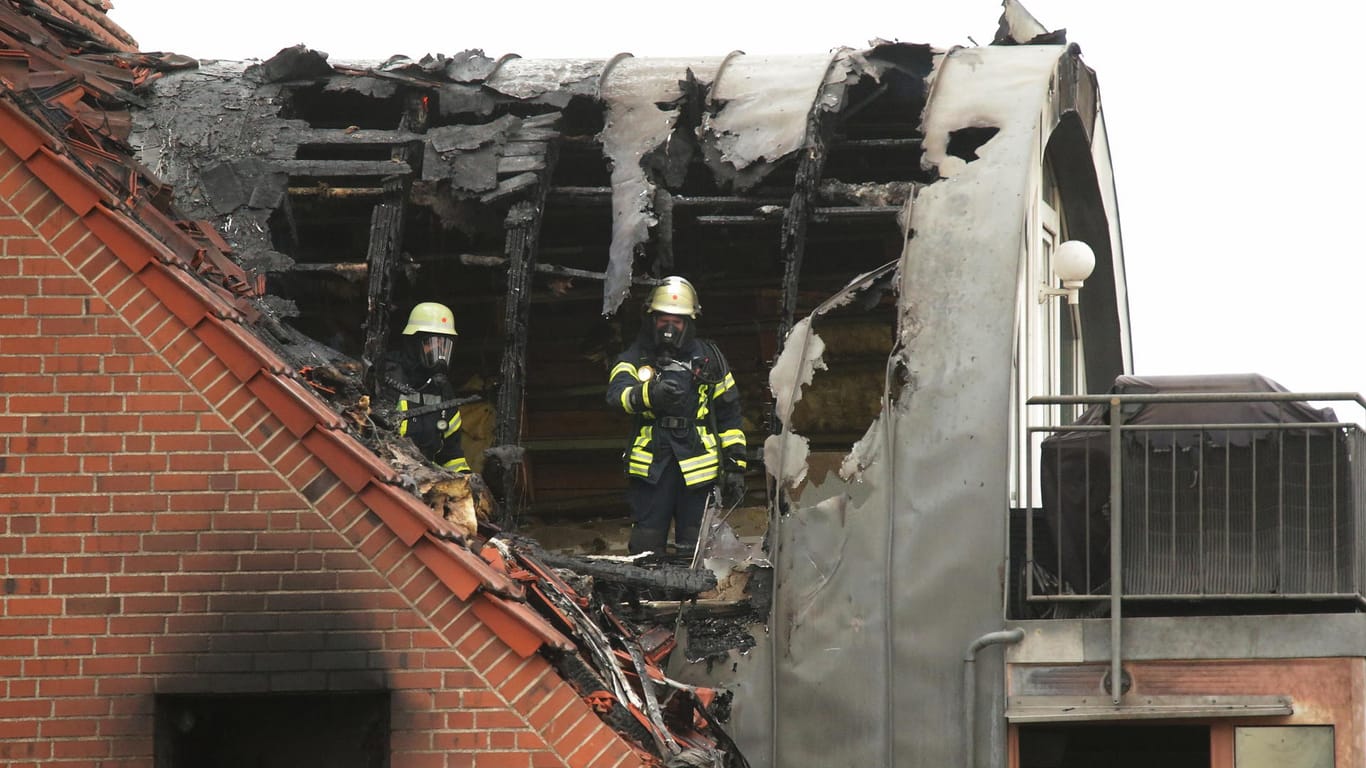 Feuerwehrleute suchen in einem beschädigten Wohnhaus nach Spuren.