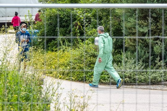 Ein Mann in Schutzanzug auf dem Gelände des betroffenen Bauernhofs.