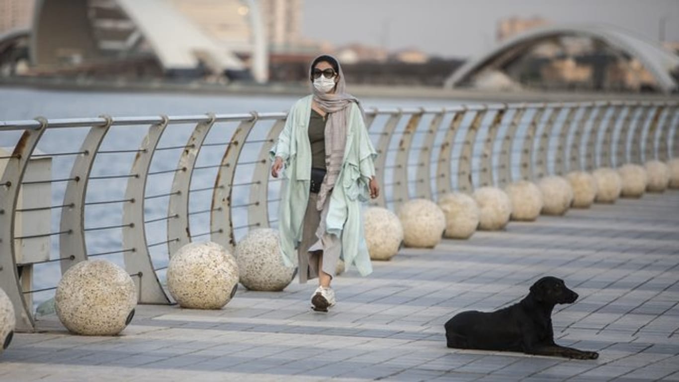 Eine Frau mit Mundschutz geht am Chitgar-See in Teheran spazieren.