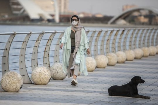 Eine Frau mit Mundschutz geht am Chitgar-See in Teheran spazieren.