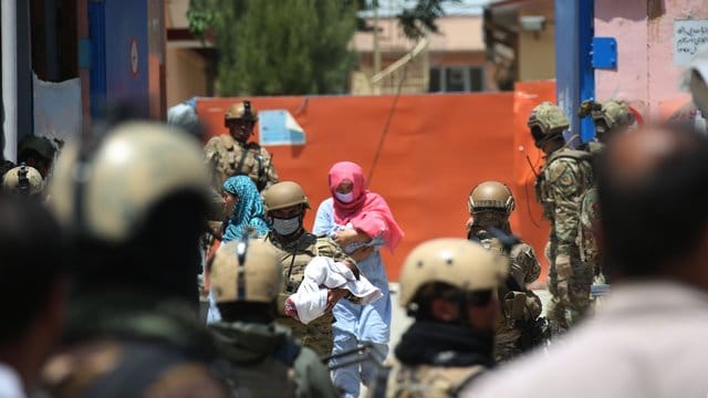 Sicherheitskräfte und Gesundheitspersonal mit Schutzmasken tragen Babys aus einem Krankenhaus nach einem Anschlag in Kabul. Sicherheitskräfte und Gesundheitspersonal mit Schutzmasken tragen Babys aus einem Krankenhaus nach einem Anschlag in Kabul.