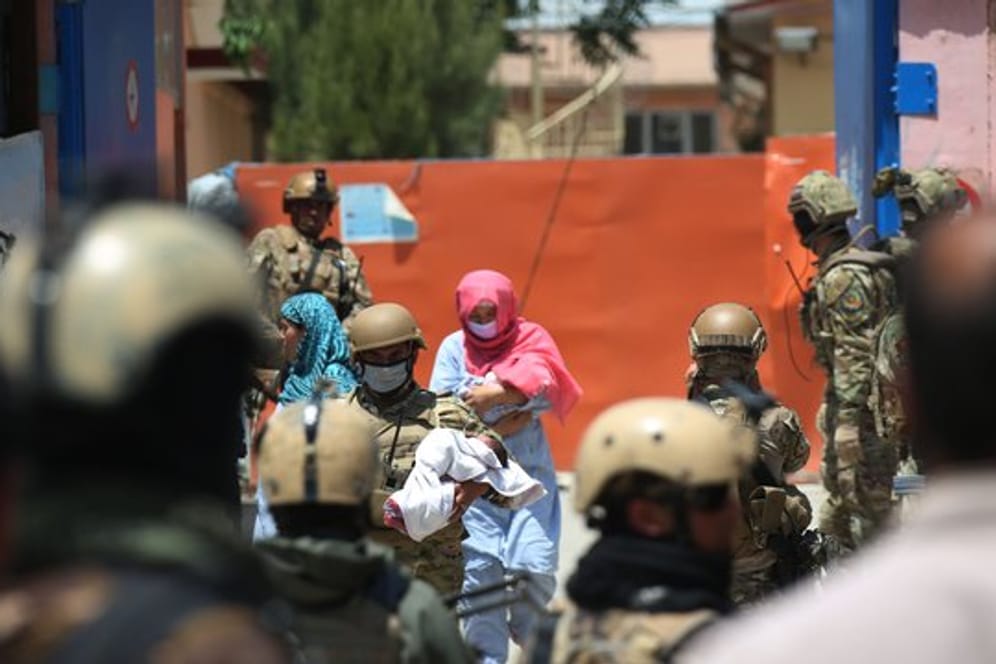 Sicherheitskräfte und Gesundheitspersonal mit Schutzmasken tragen Babys aus einem Krankenhaus nach einem Anschlag in Kabul.