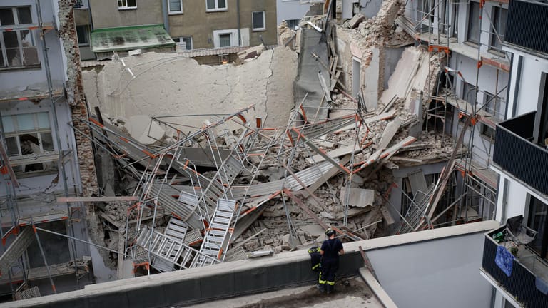 Einsatzkräfte der Feuerwehr stehen vor dem eingestürzten Gebäude und Gerüst: Im Düsseldorfer Zentrum sind bei Bauarbeiten Teile eines Gebäudes eingestürzt.