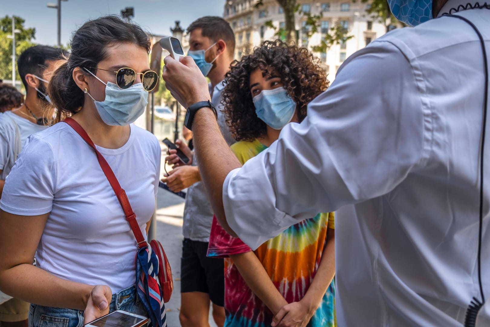 Bei Touristinnen wird vor einer Tour durch das Gaudí-Gebäude Casa Batlló in Barcelona die Temperatur gemessen: Das Auswärtige Amt rät derzeit von Reisen in die Stadt ab.