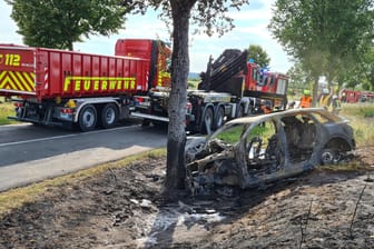 Das ausgebrannte Unfallwrack eines Autos: Eine junge Fahrerin ist in Groß Kreutz bei Potsdam mit dem Auto gegen einen Baum geprallt.