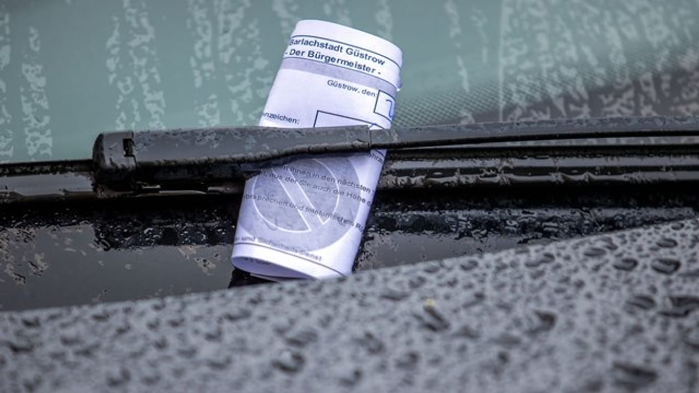Ein Knöllchen steckt unter dem Scheibenwischer eines Autos, das falsch geparkt wurde (Symbolbild): In Köln kann man Knöllchen jetzt an der Ladenkasse bezahlen.
