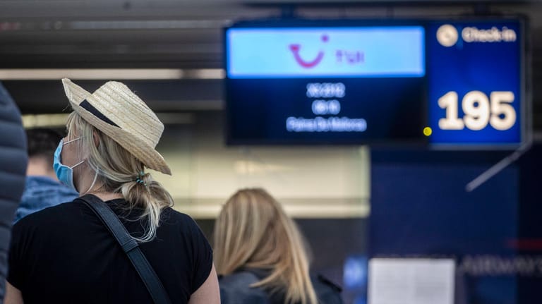 Reisende stehen am Flughafen Düsseldorf vor einem Check-In-Schalter (Symboldbil): In Wuppertal mahnt die Stadt zur Vorsicht bei der Urlaubsplanung.
