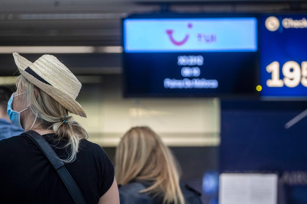 Reisende stehen am Flughafen Düsseldorf vor einem Check-In-Schalter (Symboldbil): In Wuppertal mahnt die Stadt zur Vorsicht bei der Urlaubsplanung.
