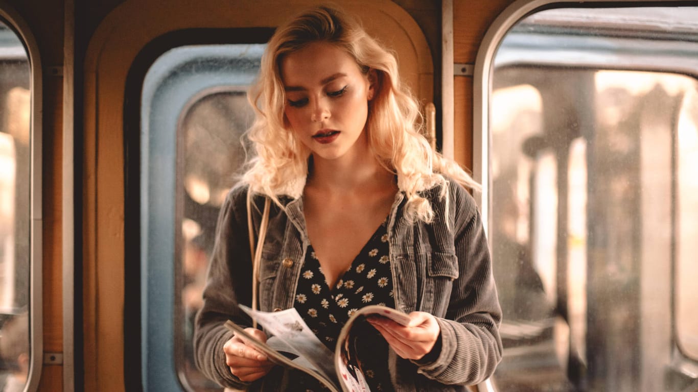 Eine junge Frau steht in einer Bahn und liest eine Zeitung (Symbolbild): In Wolfsburg sollen Jugendliche bald ein Magazin für Gleichaltrige herausgeben.