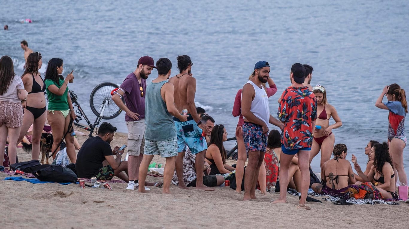 Eine Gruppe junger Menschen, dicht gedrängt an einem Strand in Barcelona: Die Corona-Zahlen in Spanien steigen, besonders in der Region Katalonien.