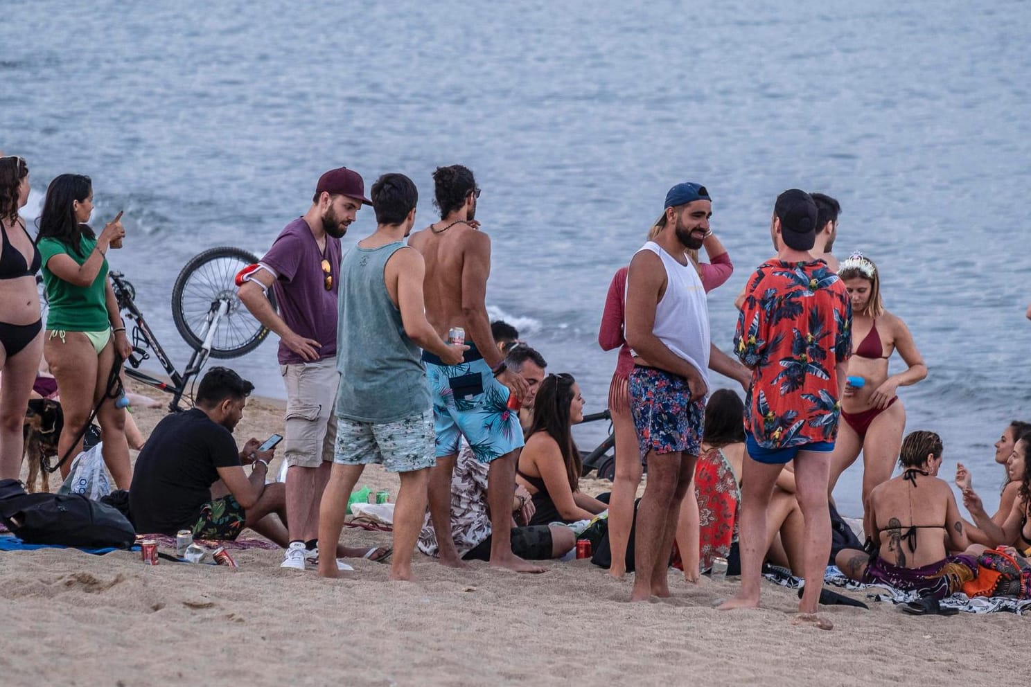 Eine Gruppe junger Menschen, dicht gedrängt an einem Strand in Barcelona: Die Corona-Zahlen in Spanien steigen, besonders in der Region Katalonien.