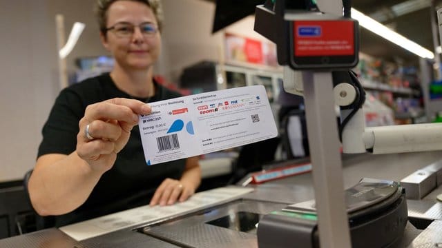 Eine Mitarbeiterin in einer Filiale des Einzelhändlers REWE hält ein Blatt mit einem Barcode in der Hand. Eine Mitarbeiterin in einer Filiale des Einzelhändlers REWE hält ein Blatt mit einem Barcode in der Hand.
