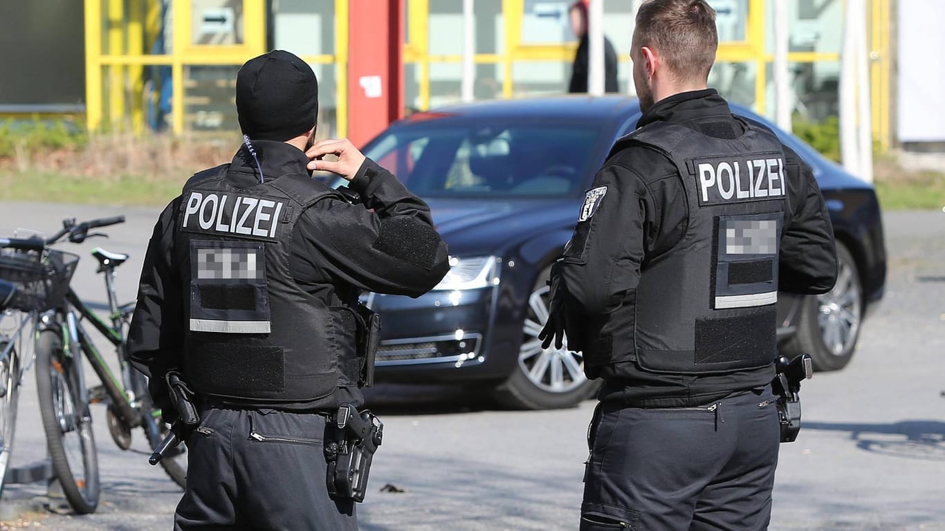 Zwei Polizisten mit schusssicheren Westen stehen vor einem Pkw (Symbolbild): In Karlsruhe sind zwei Polizisten verletzt worden.