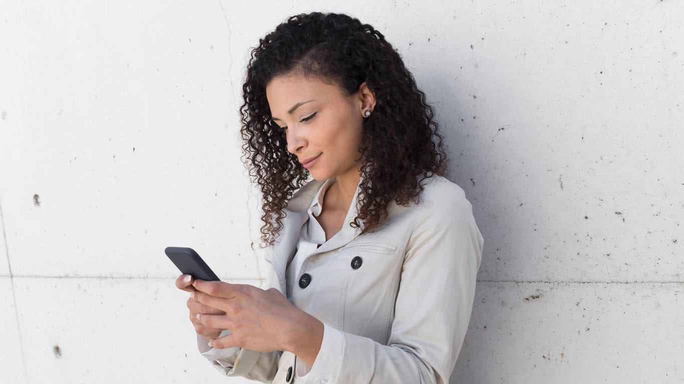 Eine Frau schaut auf ihr Handy (Symbolbild): Einen VL-Vertrag sollten Sie nicht unbedacht kündigen.
