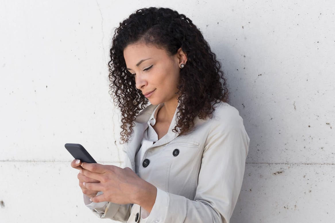 Eine Frau schaut auf ihr Handy (Symbolbild): Einen VL-Vertrag sollten Sie nicht unbedacht kündigen.