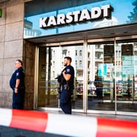 Schwer bewaffnete Polizeibeamte stehen an einem Kaufhaus am Hermannplatz: In Berlin-Neukölln war die Polizei wegen eines Raubüberfalls im Einsatz.