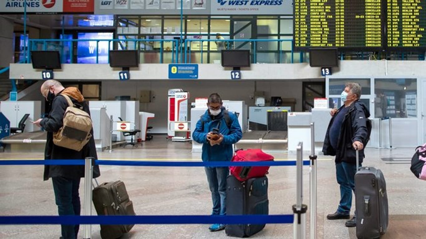 Passagiere mit Smartphones in einer Schlange im Internationalen Flughafen von Vilnius.