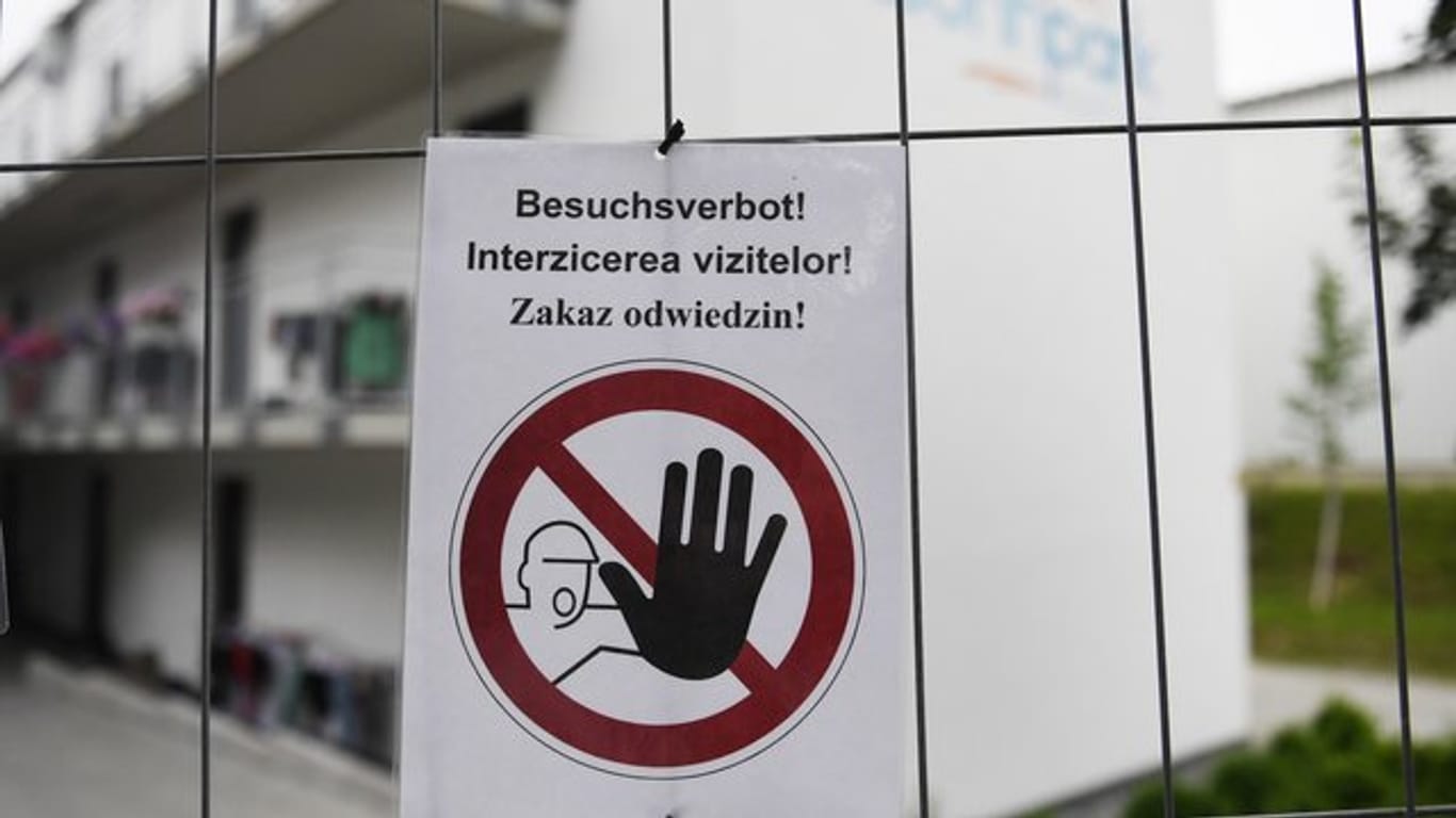 "Besuchsverbot!" steht auf deutsch, rumänisch und polnisch auf einem Zettel an einem Bauzaun, der die Wohngebäude eines Betriebes umzäunt.