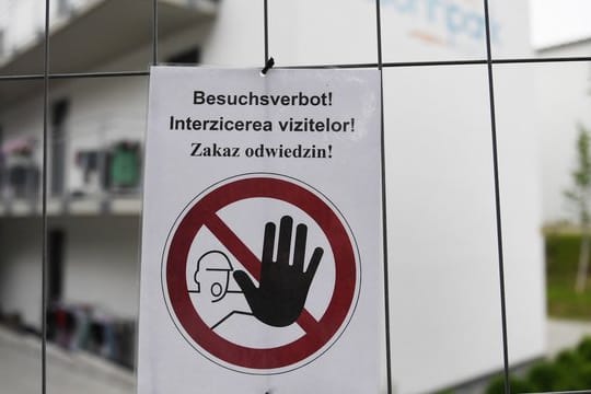 "Besuchsverbot!" steht auf deutsch, rumänisch und polnisch auf einem Zettel an einem Bauzaun, der die Wohngebäude eines Betriebes umzäunt.