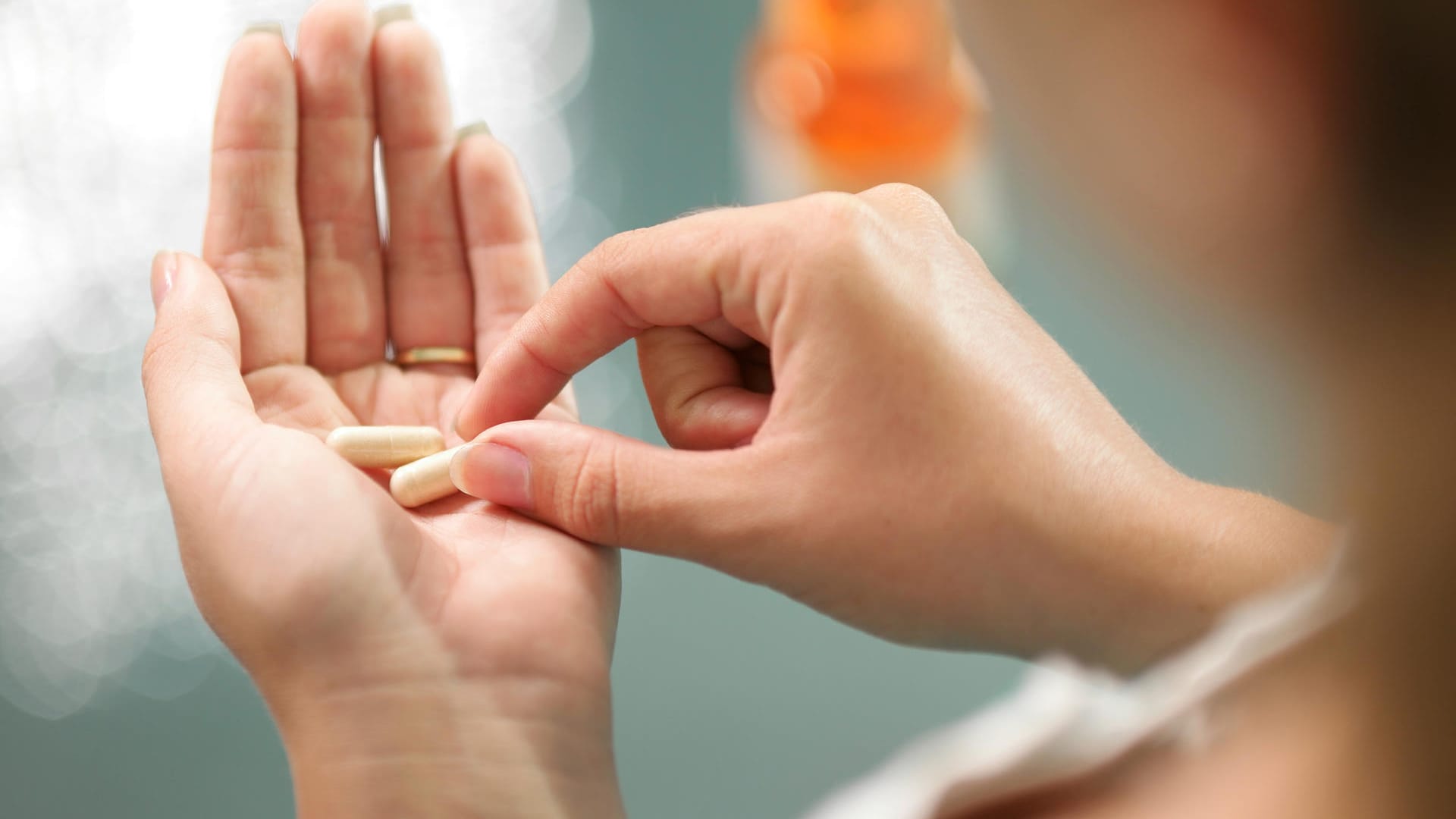 Eine Frau hält Kapseln in der Hand: Osteoporose-Medikamente können den Knochenabbau bremsen und so das Risiko von Brüchen senken.