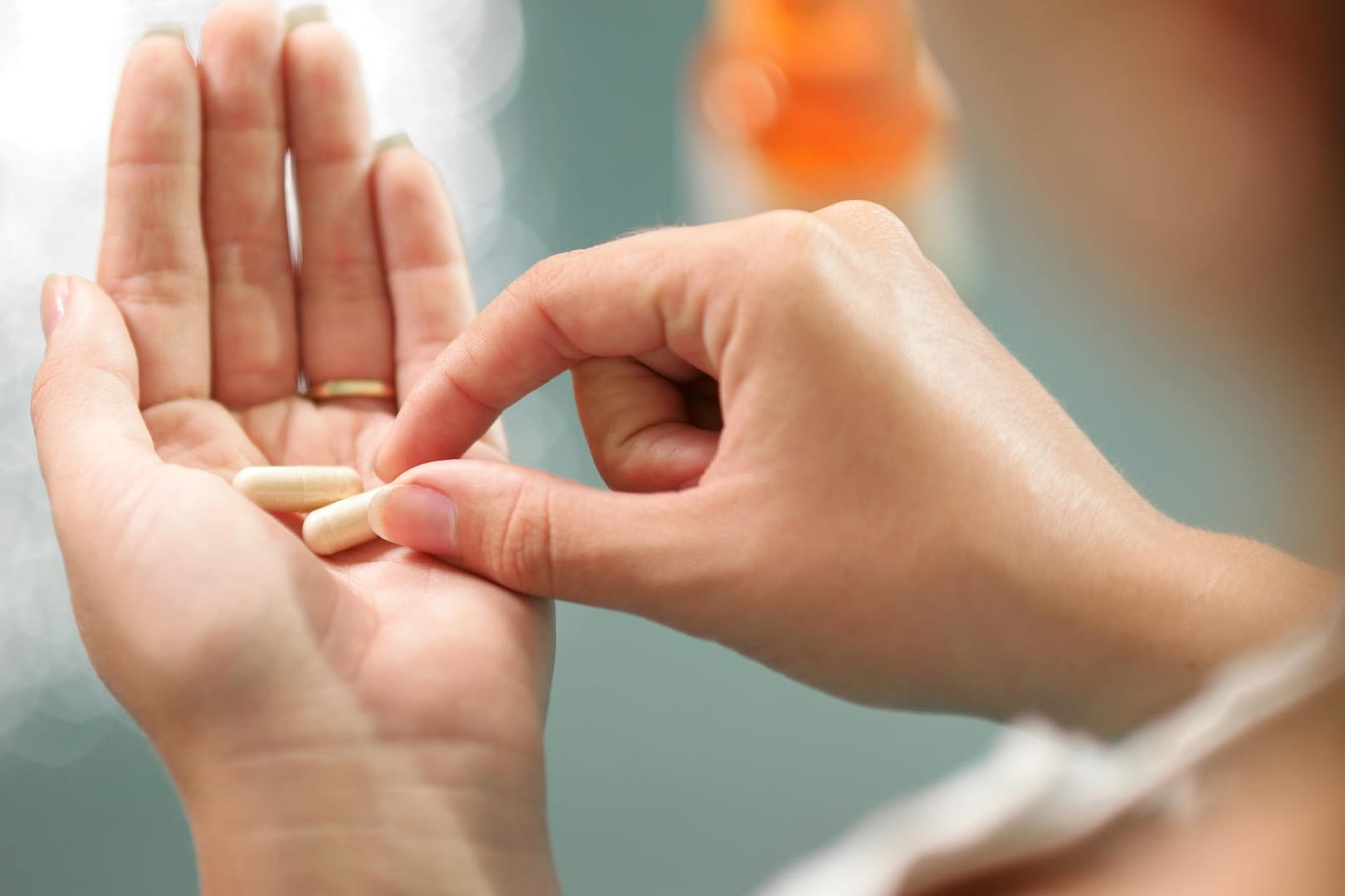 Eine Frau hält Kapseln in der Hand: Osteoporose-Medikamente können den Knochenabbau bremsen und so das Risiko von Brüchen senken.