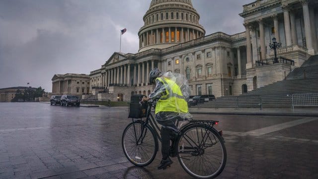 Eine Fahrradfahrerin kämpft auf dem Capitol Hill in Washington gegen Wind und starken Regen. Eine Fahrradfahrerin kämpft auf dem Capitol Hill in Washington gegen Wind und starken Regen.