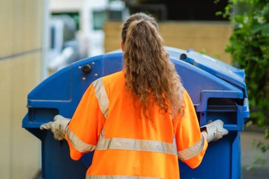 Die Studentin Laura schiebt eine Papierabfalltonne zum Abfallsammelfahrzeug.