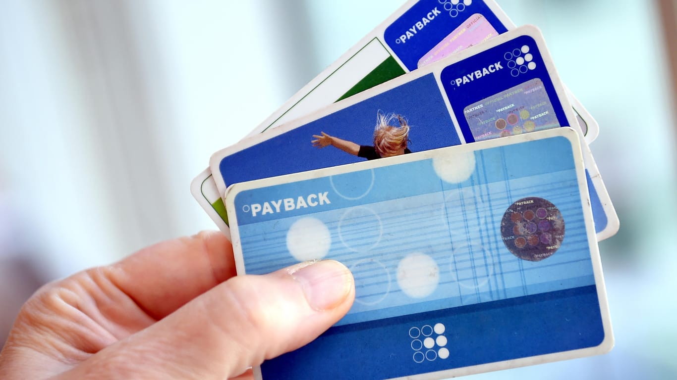 Eine Hand hält mehrere Payback-Karten: Vor allem bei den Prämien sollten Nutzer wachsam sein.