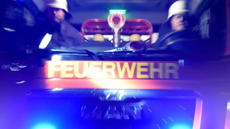 Feuerwehrmänner in einem Löschfahrzeug (Symbolbild): Zwei Autos haben in einem Frankfurter Parkhaus Feuer gefangen.