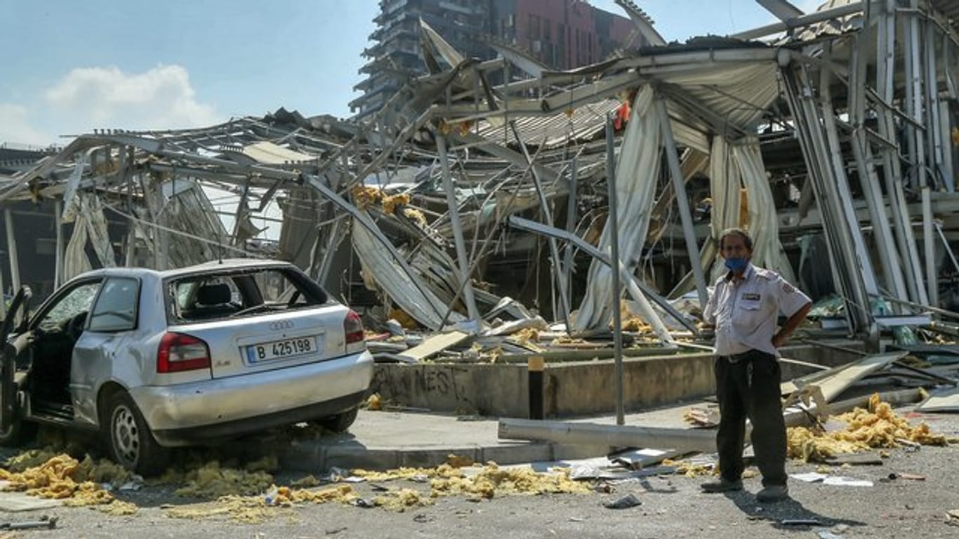 Ein Wachmann eines Autohauses steht vor den zerstörten Geschäftsräumen.