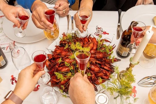 Unterbrochen wird das Knacken und Pulen beim traditionellen schwedischen Krebsessen mit einem Prösterchen ("Skål") und einem Lied.