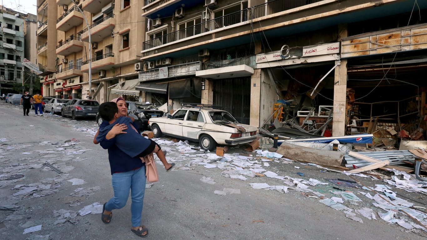 Frau trägt Kind durch die Straßen von Beirut: Nach der schweren Explosion bieten zahlreiche Staaten ihre Hilfe an.