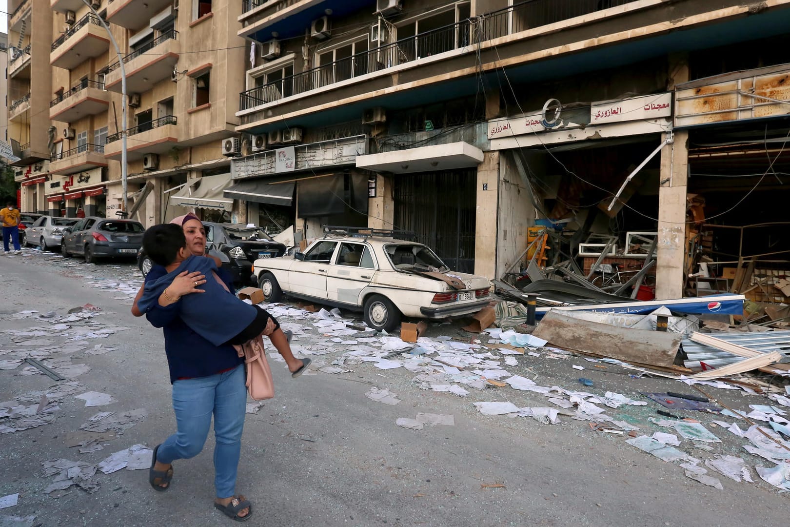 Frau trägt Kind durch die Straßen von Beirut: Nach der schweren Explosion bieten zahlreiche Staaten ihre Hilfe an.