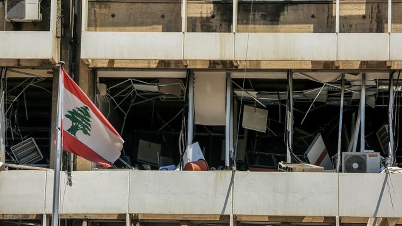 Die libanesische Flagge vor der Fassade eines zerstörten Bürogebäudes in Beirut.