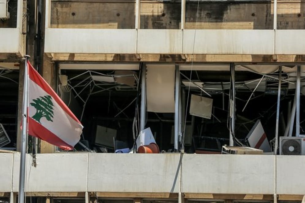 Die libanesische Flagge vor der Fassade eines zerstörten Bürogebäudes in Beirut.