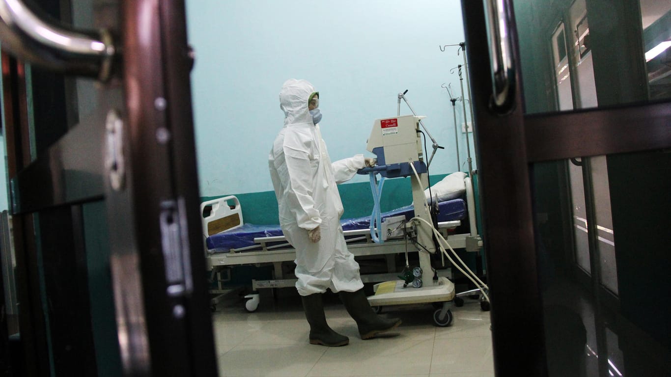 Geschützt vor einer Corona-Infektion: Krankenhauspersonal bereitet einen Raum speziell für Covid-19-Patienten vor.