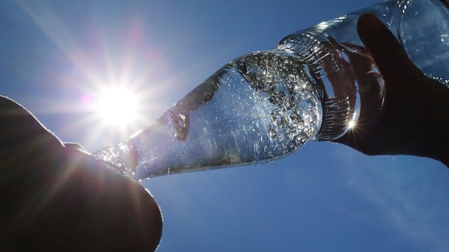 Eine Frau trinkt aus einer Flasche Mineralwasser Eine Frau trinkt aus einer Flasche Mineralwasser