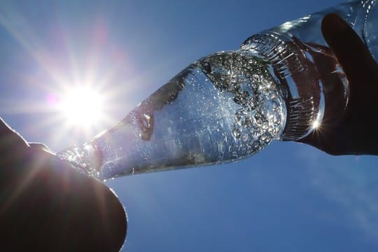 Eine Frau trinkt aus einer Flasche Mineralwasser