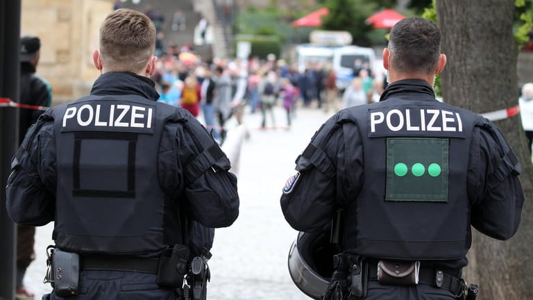 Polizisten stehen in Erfurt mit dem Rücken zur Kamera (Symbolbild): Die Polizei hat Ermittlungen zu einer erneuten offenbar rassistisch motivierten Tat in Erfurt übernommen.